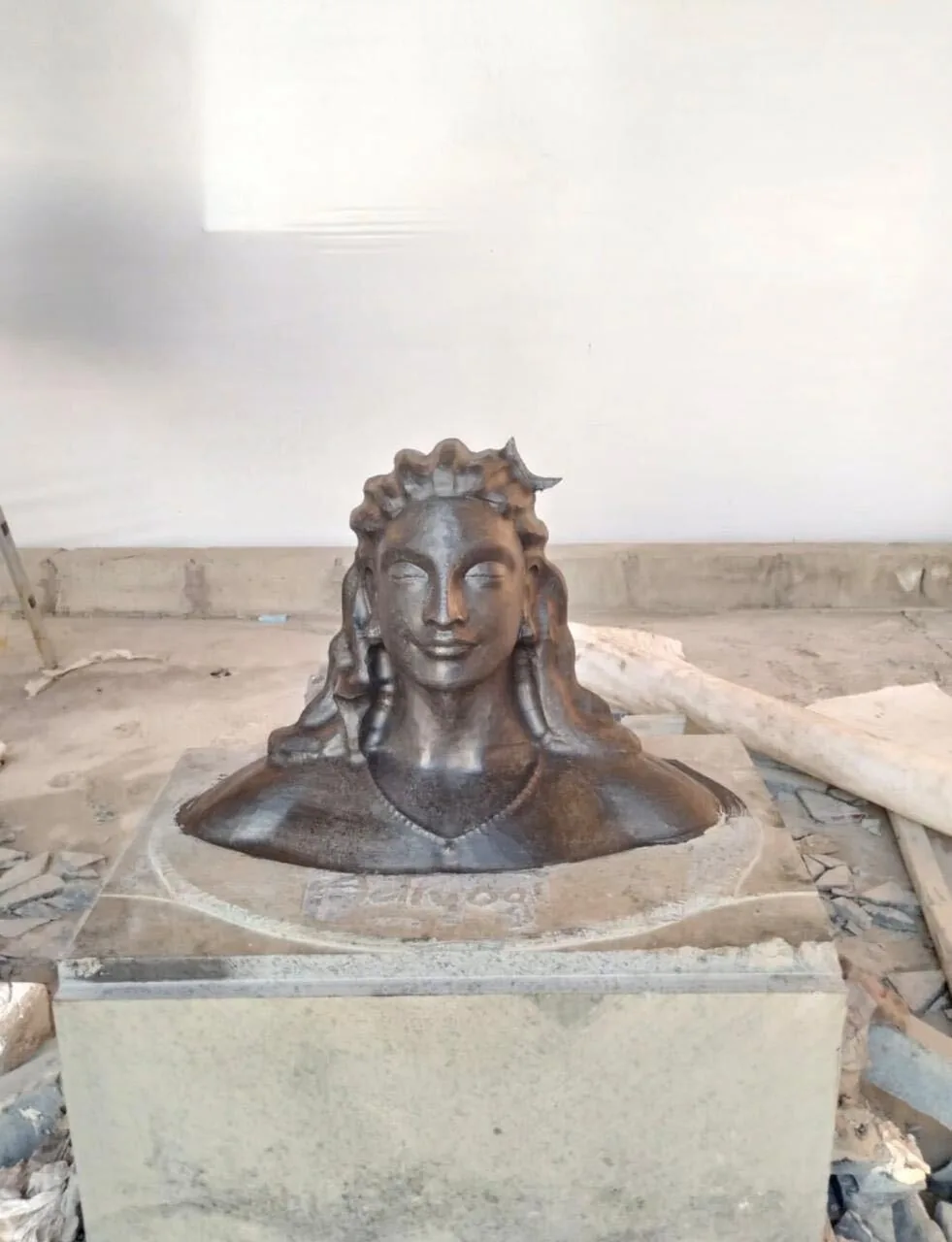 Adiyogi bust in dark stone, set into a carved plinth in the workshop